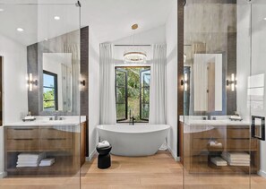 Un bagno moderno con una vasca freestanding, due lavabi e ampi specchi.