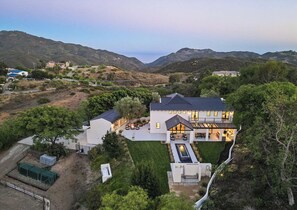 Una casa moderna con un ampio patio, immersa tra le colline.
