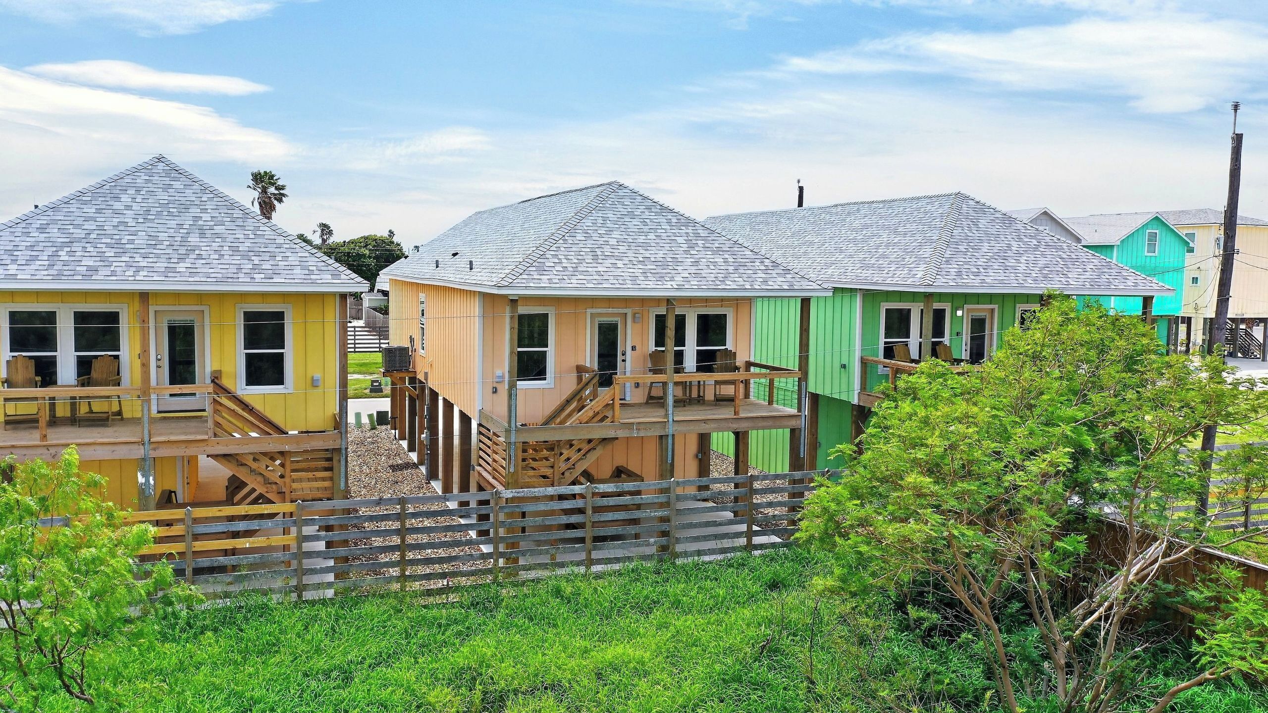A row of colorful wooden cabins with external staircases and a wooden fence in the foreground.