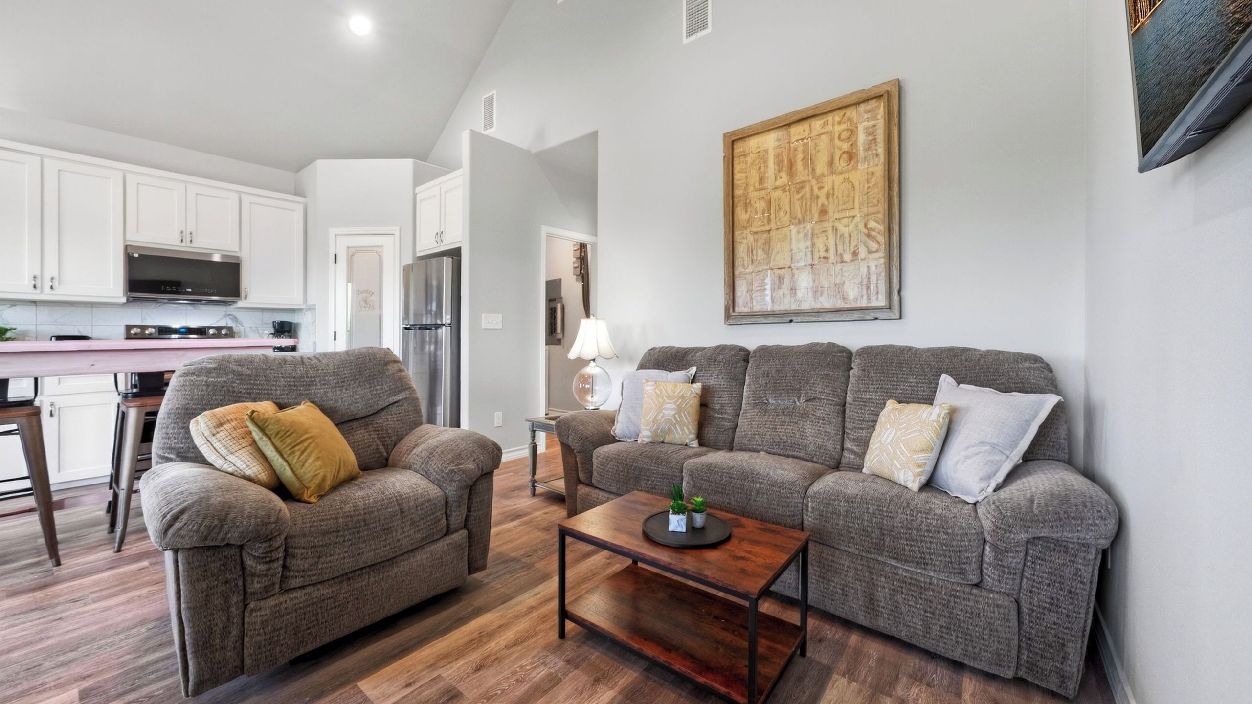 A living room with two sofas, a coffee table, and a kitchen in the background.