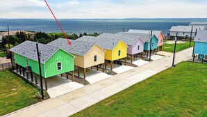 Una hilera de casas de madera coloridas con vista al océano y un puente a lo lejos.