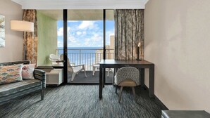 Habitación de hotel con balcón, sofá, escritorio y una silla.