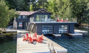 Une péniche moderne dotée d’une terrasse, de sièges extérieurs et offrant une vue sur l’eau.