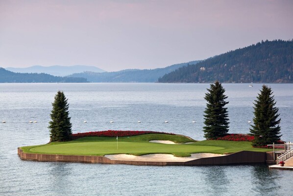 A golf course with a water body in the foreground and mountains in the background. - Chateau CDA | Quick Drive to Restaurants & Coeur d'Alene Lake! (Coeur d'Alene)