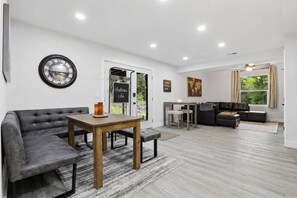 A modern living room with a grey sofa, wooden coffee table, and a dining area with a small table and chairs. - Chateau CDA | Quick Drive to Restaurants & Coeur d'Alene Lake! (Coeur d'Alene)