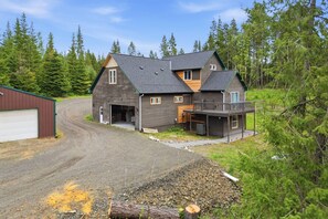 A two-story house with a garage, a covered porch, and a driveway leading to a gravel area. - Chateau CDA | Quick Drive to Restaurants & Coeur d'Alene Lake! (Coeur d'Alene)