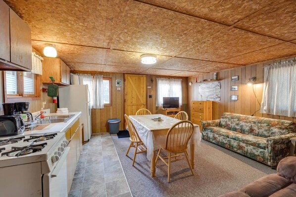 A compact RV interior with a kitchenette, dining area, and living space. - Birch at Hiawatha Cabins (Munising Township)