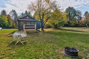 Eine Hütte mit Terrasse, Feuerstelle und Gartenmöbeln.