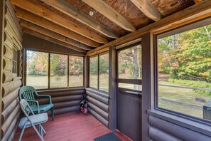 Eine Blockhütte mit Veranda, einem grünen Stuhl und einer roten Matte.