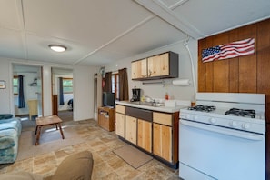 A compact kitchen with wooden cabinets, a stove, and a small dining area.