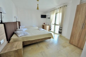 Habitación de hotel con cama, mesitas de noche, televisión, armario y ventana con cortinas.