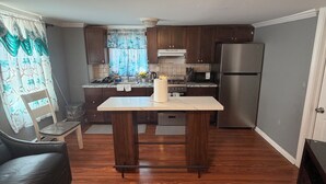 A kitchen with a central island, wooden cabinets, a refrigerator, and a dining area with a sofa. - Cozy 1-bedroom house in welcoming Bridgeport (Bridgeport)