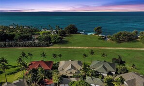 A golf course with a view of the ocean, surrounded by houses and palm trees.