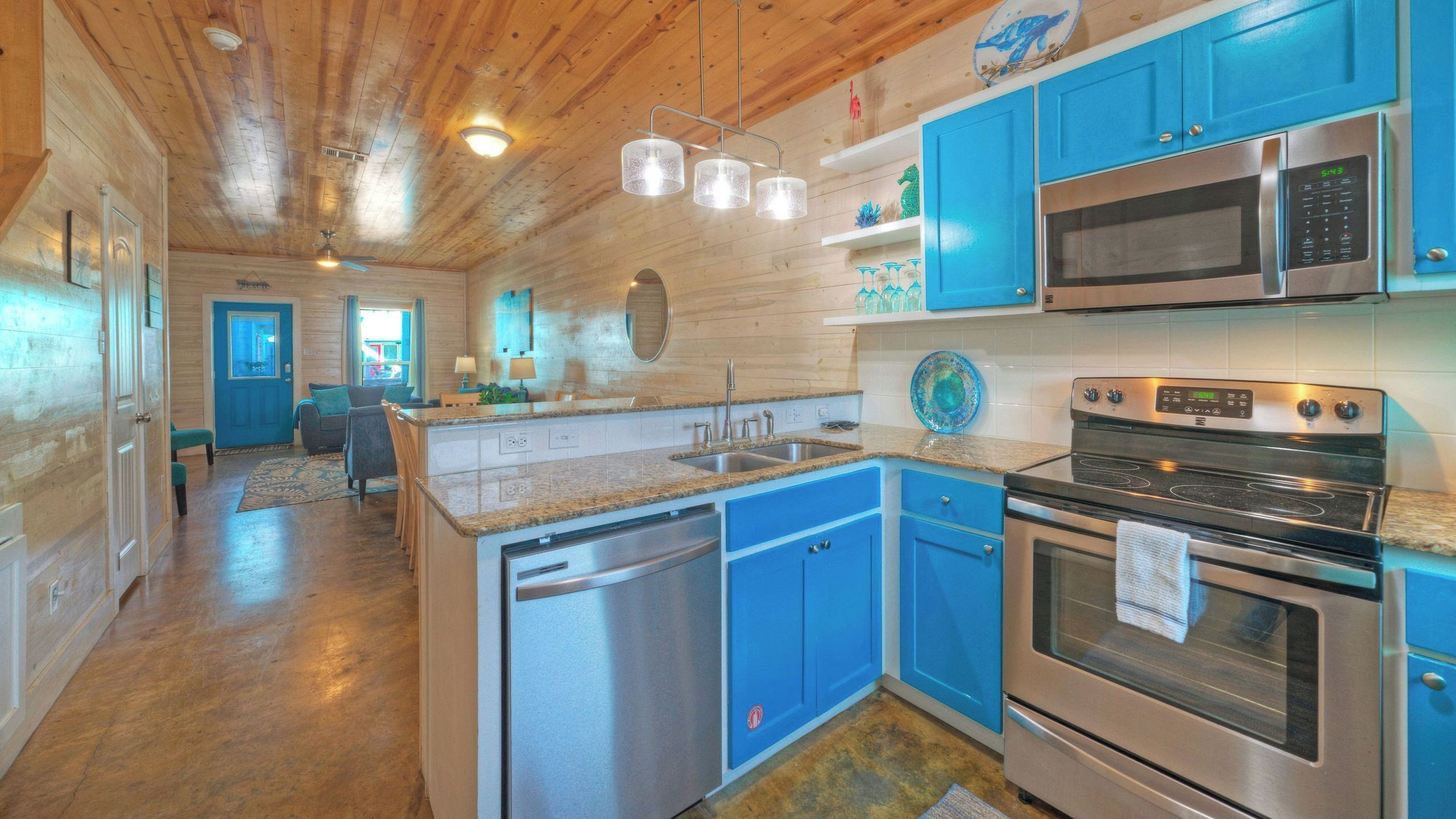 A kitchen with blue cabinets, stainless steel appliances, and a wooden ceiling.