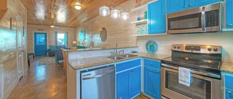A kitchen with blue cabinets, stainless steel appliances, and a wooden ceiling.