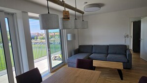 Een moderne woonkamer met een grijze bank, een houten salontafel en hanglampen.