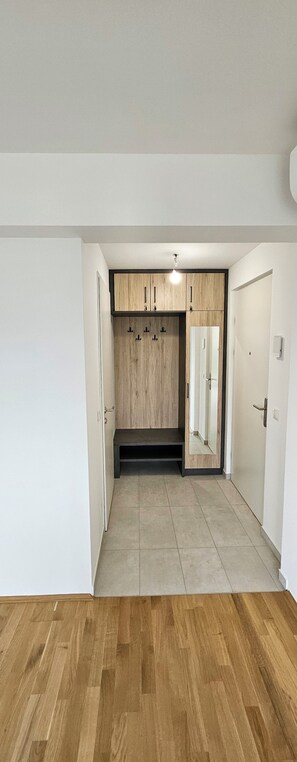 Ein Zimmer mit Holzboden, einer eingebauten Sitzbank und einem Kleiderschrank mit Spiegel.