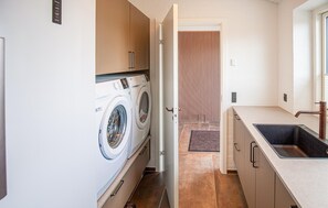 A laundry room with a washing machine, a sink, and a door leading to a hallway. - Lovely home in Vinderup with WiFi (Vinderup)