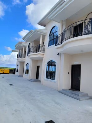 Un edificio residencial de varios pisos con balcones, ventanas amplias y techo plano.