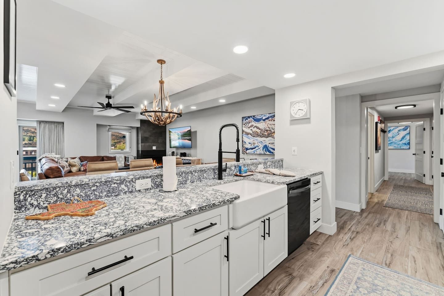 A modern kitchen with granite countertops, white cabinetry, and a built-in dishwasher.