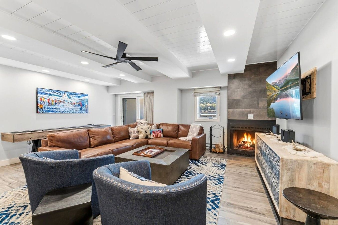 A modern living room with a fireplace, leather sofa, and a flat-screen TV.