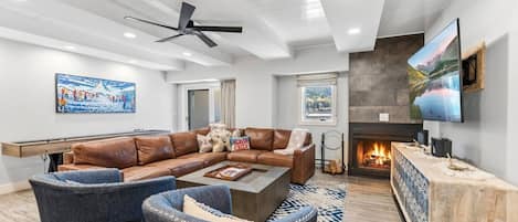 A modern living room with a fireplace, leather sofa, and a flat-screen TV.