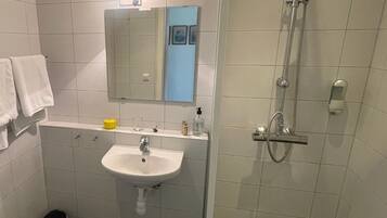 A bathroom with a sink, mirror, shower, and toilet.