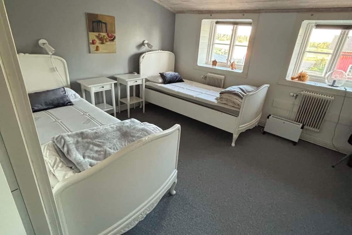 A room with a bed, a small table, a radiator, and a window.
