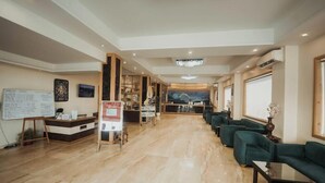A hotel lobby with a reception desk, seating area, and a mural on the wall. - D'polo Club & Spa Resort (Dharamshala)
