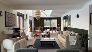 A modern living room with a sofa, armchairs, a coffee table, and a dining area with chairs and a table. - Maison Familiale Premium - 20min from Honfleur (Martainville)