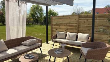 An outdoor patio with wicker furniture, a round table, and a pergola.