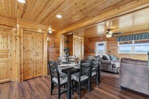 A wooden interior with a dining table, chairs, a sofa, and a ceiling fan. - Elk Ridge Retreat | Hot Tub & 360° Views (Park County)