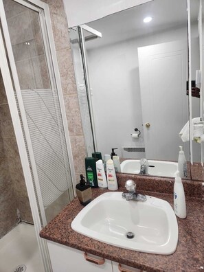A bathroom with a sink, mirror, and toiletries.