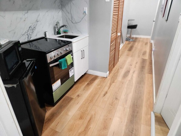 A kitchen with a stove, oven, sink, and wooden flooring.