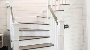 Eine weiße Treppe mit Handlauf, die zu einer Zwischenebene mit einem Schild führt.