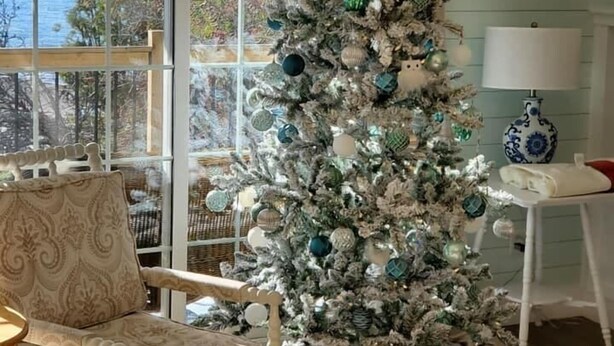 Ein Zimmer mit Weihnachtsbaum, einem Sessel, einer Lampe und Blick ins Freie.