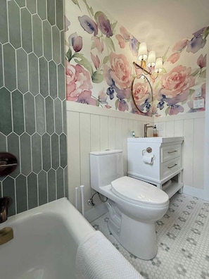Un baño con inodoro blanco, lavabo blanco, tocador blanco y zona de ducha.