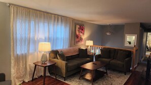 A living room with a sofa, two side tables with lamps, a coffee table, and a patterned rug. - The Heron's Perch - HL (Hampton)