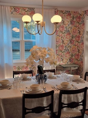 A dining table set with plates, glasses, and a vase of flowers. - The Heron's Perch - HL (Hampton)