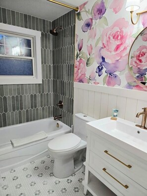 Un baño con bañera, inodoro y tocador con cajones.