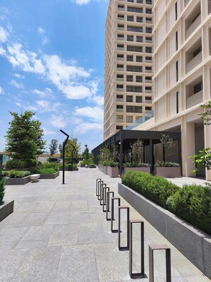 A modern building with a long, straight pathway lined with rectangular planters and a row of black poles. - Apartment with city view in Zapopan, Jalisco (Zapopan)