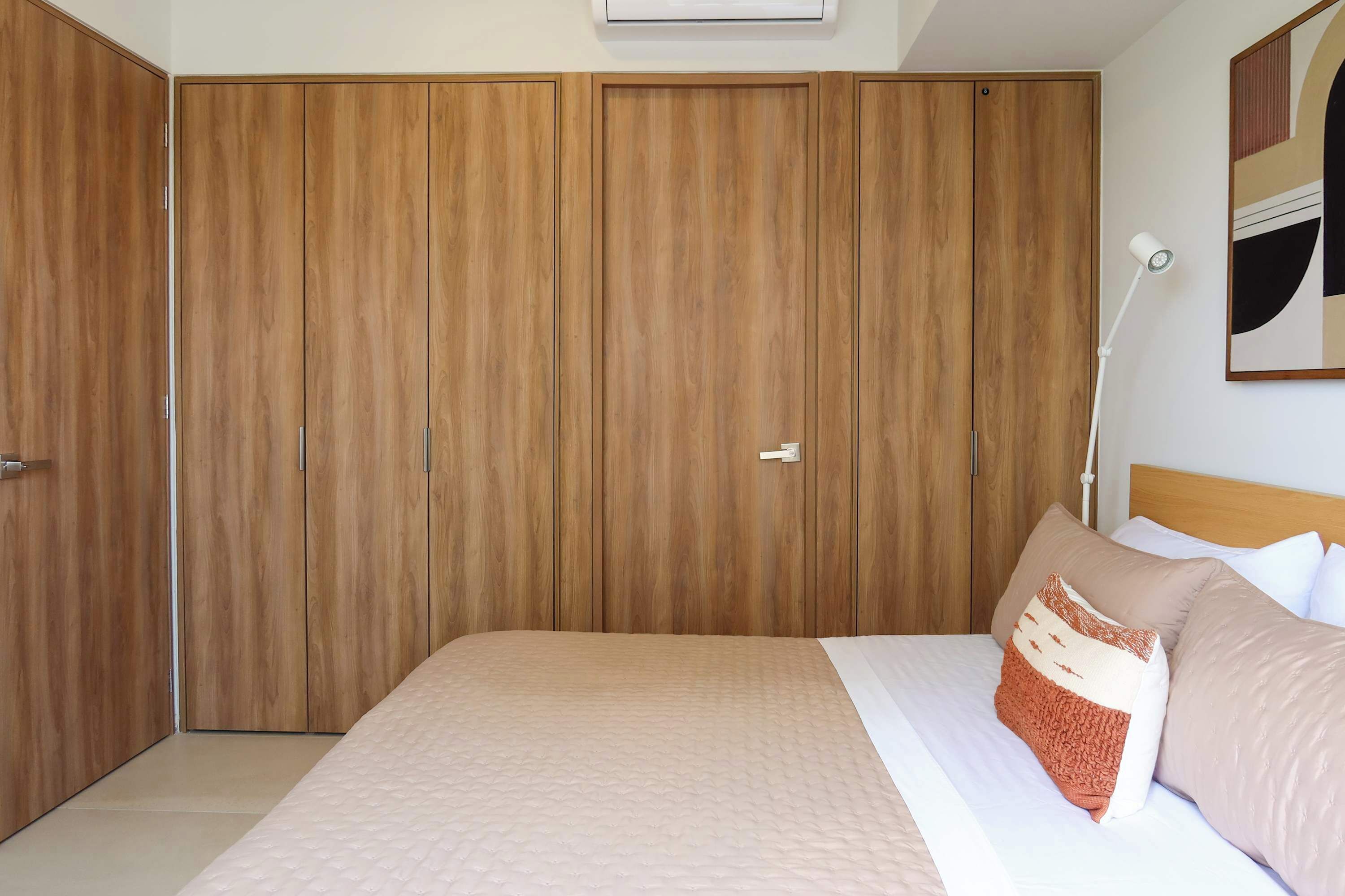 Ein Schlafzimmer mit einem großen Bett, einem Kleiderschrank und einer Nachttischlampe.