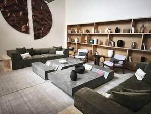 A modern living room with a sectional sofa, a coffee table, and a bookshelf filled with decorative items. - Apartment with city view in Zapopan, Jalisco (Zapopan)
