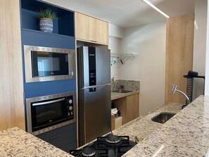 A kitchen with a built-in oven, microwave, refrigerator, and gas stove. - Bela Hospedagem - Imperial Bessa 121 (João Pessoa)