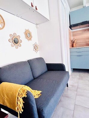 Ein modernes Wohnzimmer mit einem grauen Sofa, einer gelben Decke und Wandbildern.