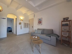 Ein Wohnzimmer mit grauem Sofa, einem runden Holztisch und einem Bücherregal.