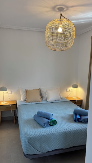 Ein Schlafzimmer mit einem Bett, zwei Nachttischen, einer Pendelleuchte und einer Wandsteckdose.