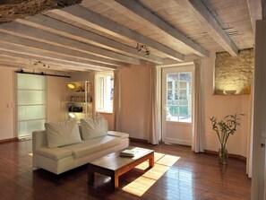 A living room with a white sofa, wooden coffee table, and a bookshelf. - In the quiet of the countryside - Authentic charm - Modern comfort - Air-conditioned (Touvérac)