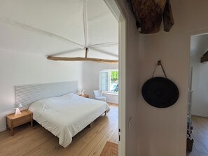 A bedroom with a bed, bedside tables, a hanging light fixture, and a view of the outdoors. - In the quiet of the countryside - Authentic charm - Modern comfort - Air-conditioned (Touvérac)