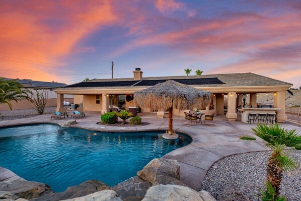 Una casa con piscina, zona de estar al aire libre y bar.